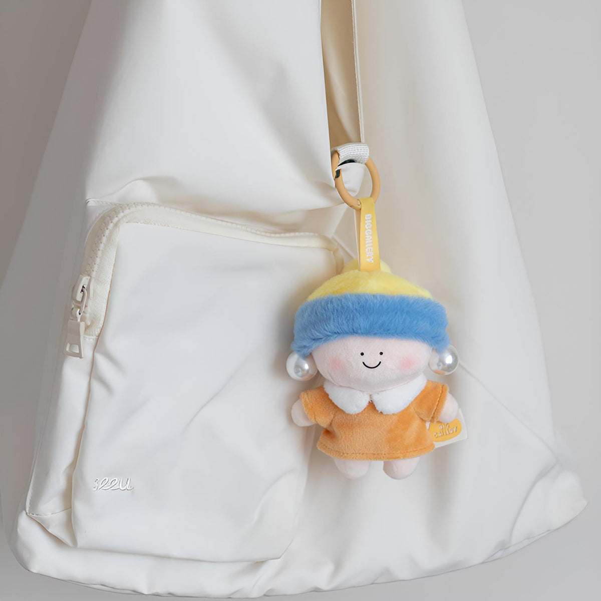 Girl with a Pearl Earring Plush Charm clipped to a bag, a cute plush bag accessory inspired by classic art