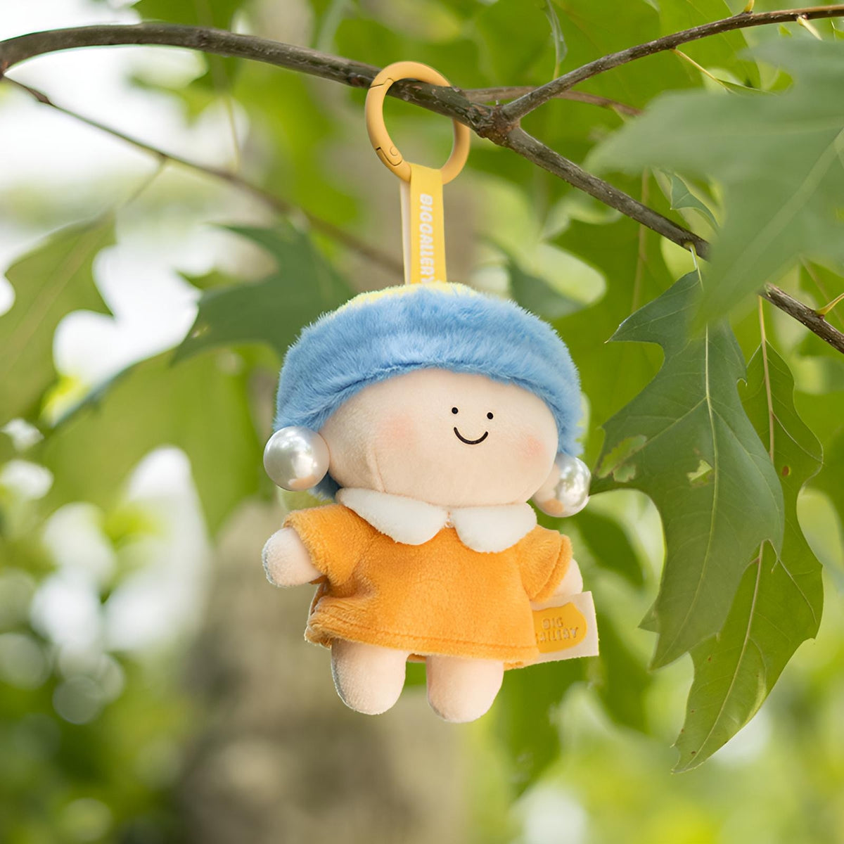 Girl with a Pearl Earring Plush Charm hanging outdoors, featuring a soft plush body, pearl earrings, and collectible art style